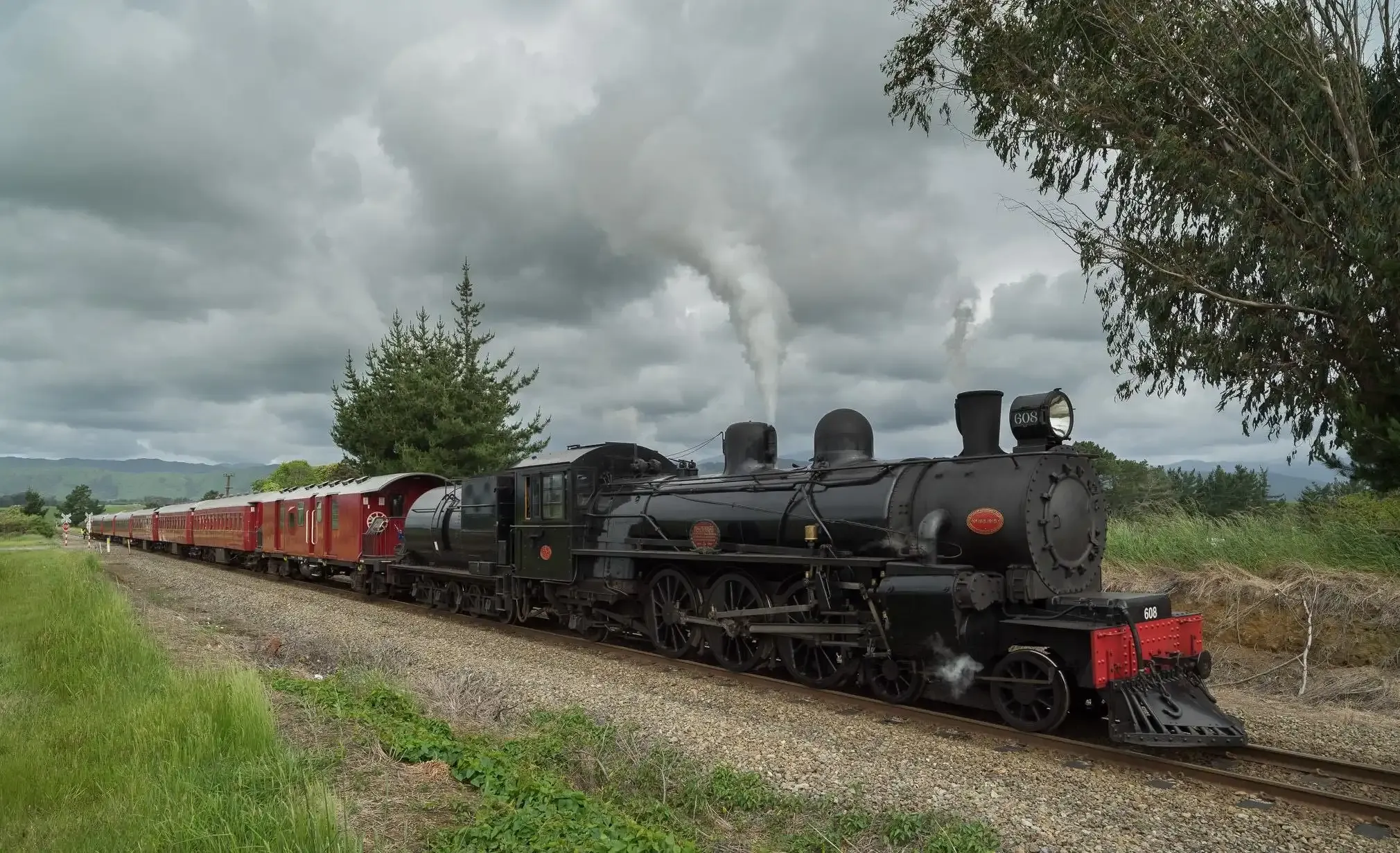 A steam locomotive pulling vintage carriages through green countryside