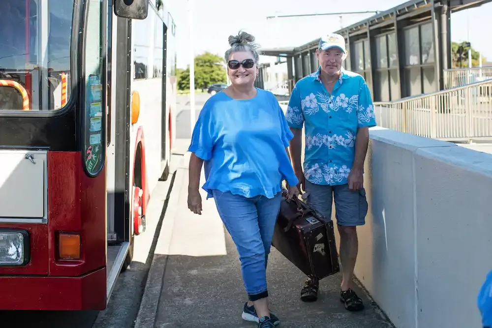 Two guests walking from the vintage bus with their luggage